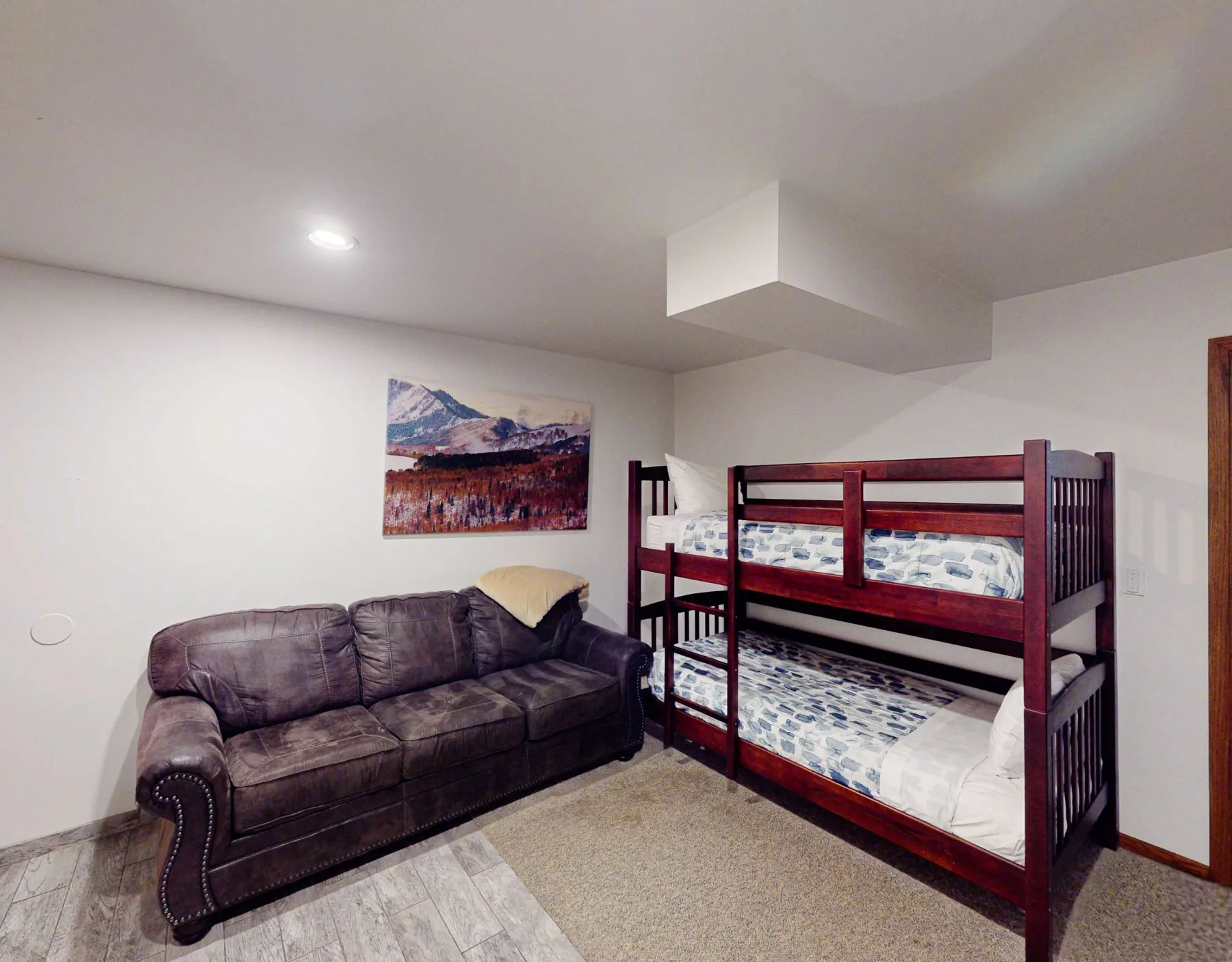 Un dormitorio con literas y un sofá junto a una pintura en la pared.