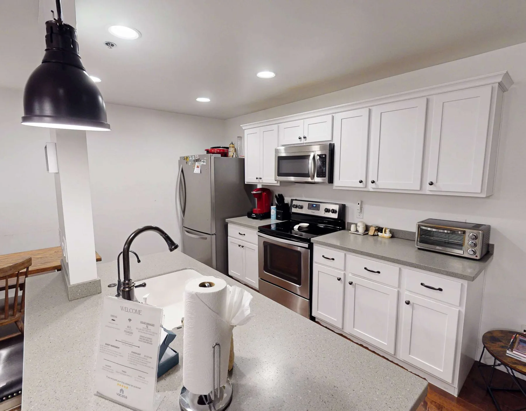 Una cocina luminosa con gabinetes blancos, electrodomésticos de acero inoxidable y una península.