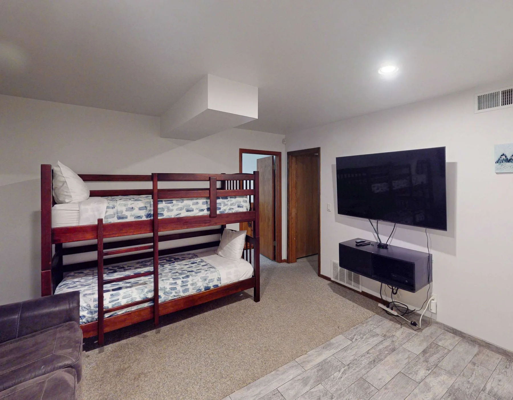 Un dormitorio con una litera de madera y un televisor montado en la pared.