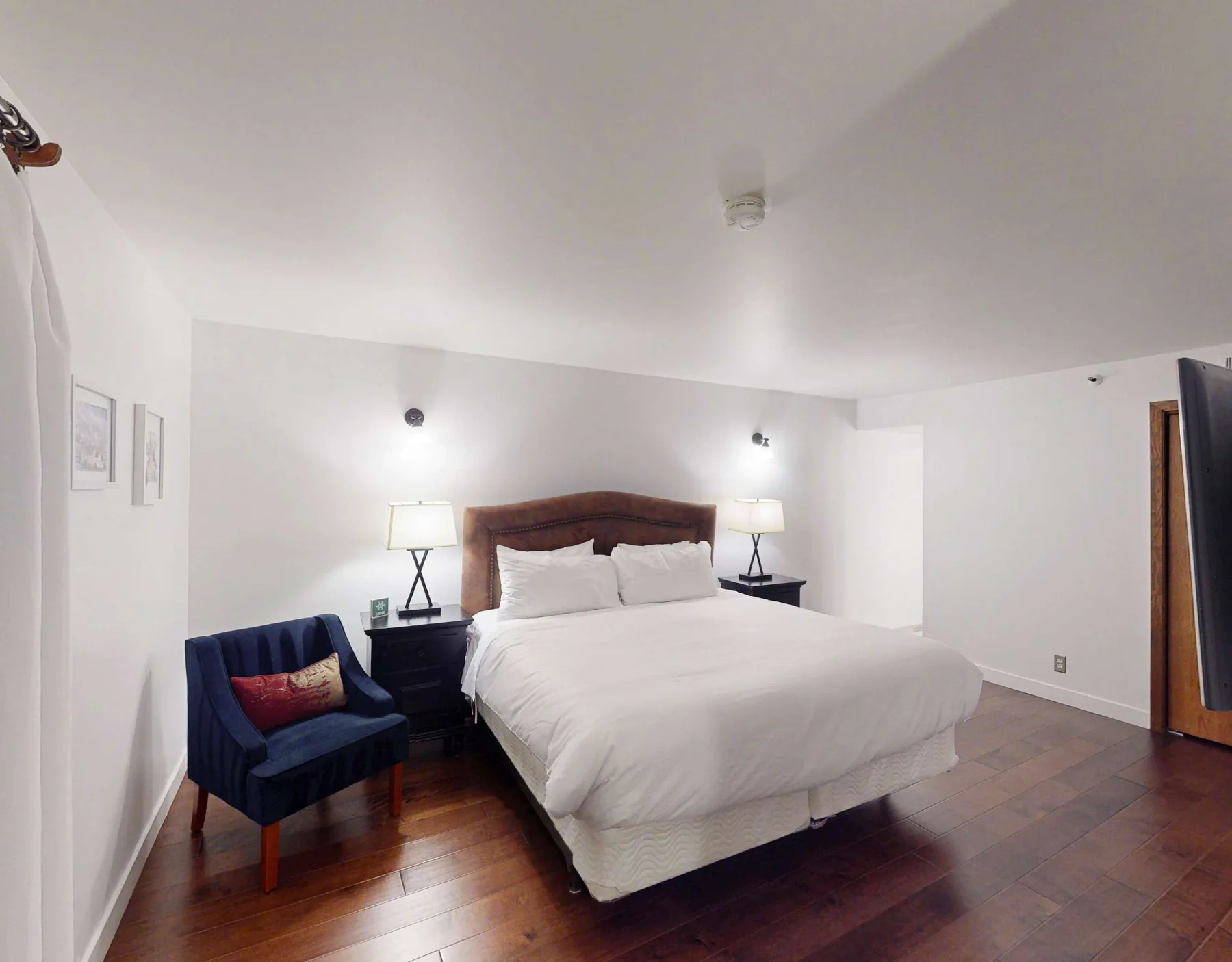 Un dormitorio con una cama, mesas de noche y un sillón azul.