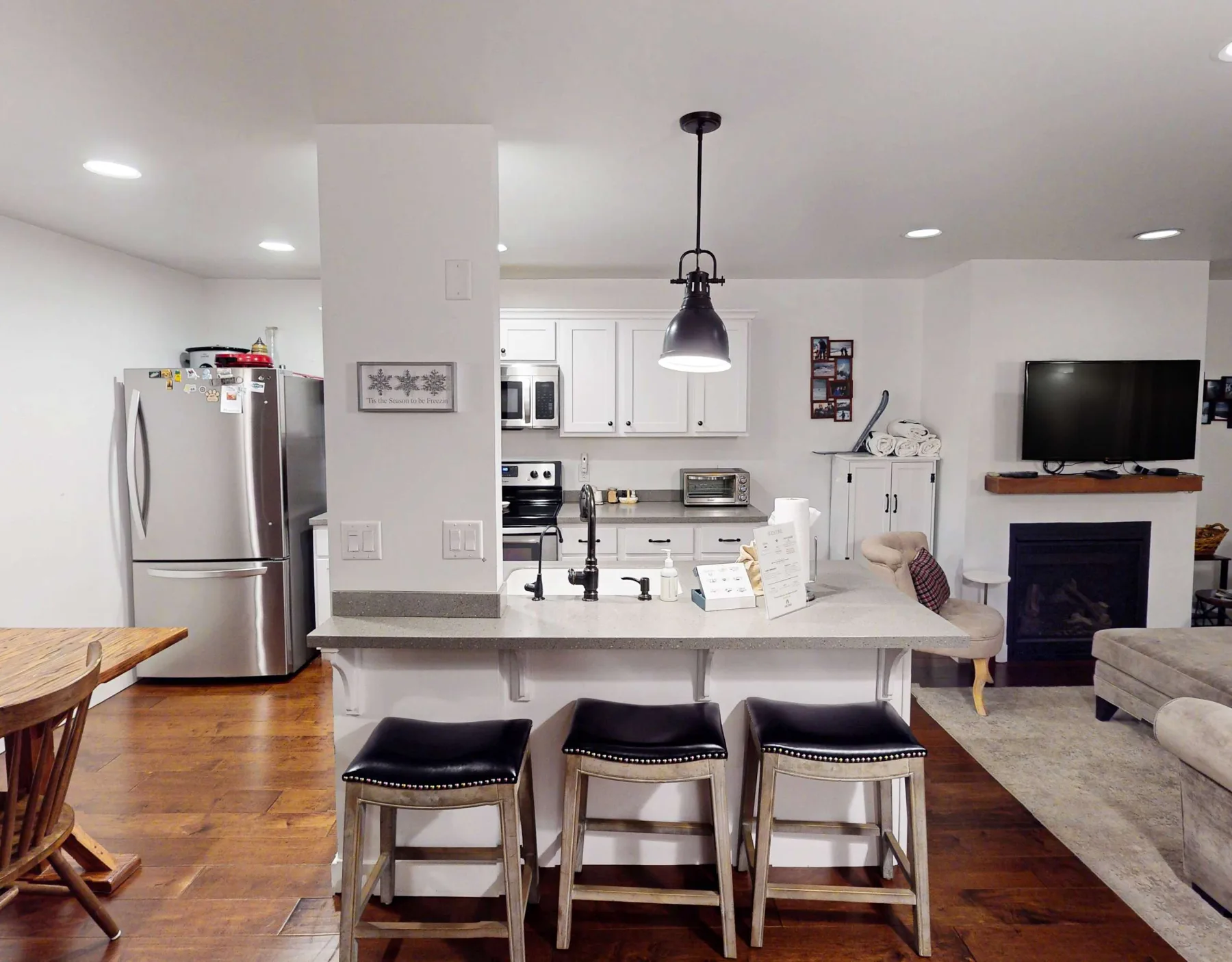 Cocina y sala de estar abiertas, con una barra de desayuno y un televisor.