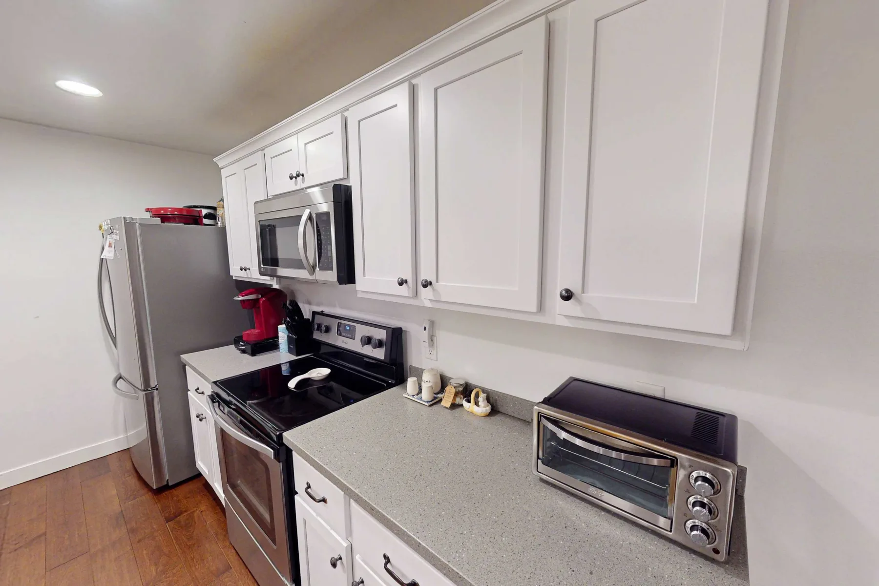 Una cocina con gabinetes blancos, un refrigerador y electrodomésticos sobre la encimera.