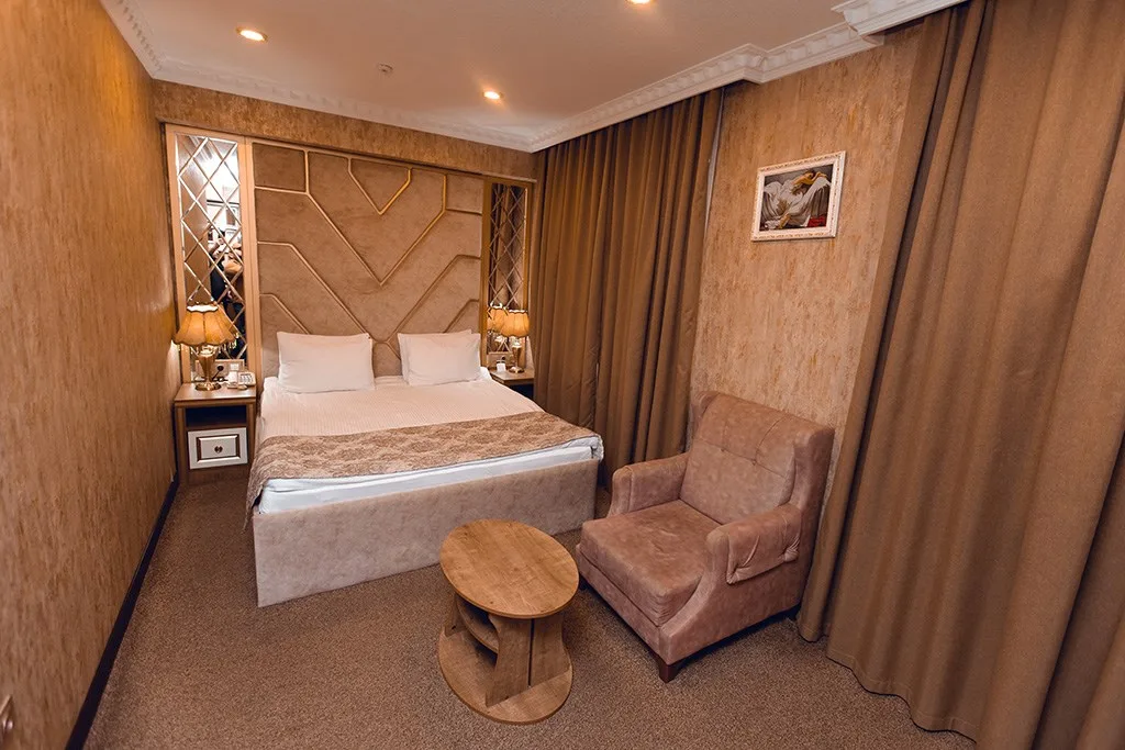 Representative hotel space: A bedroom with a bed, bedside tables, and an upholstered chair.