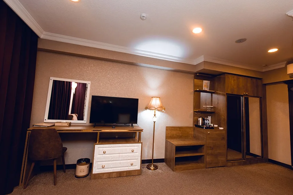 Representative hotel space: A hotel room with a desk, television, and wooden storage unit.