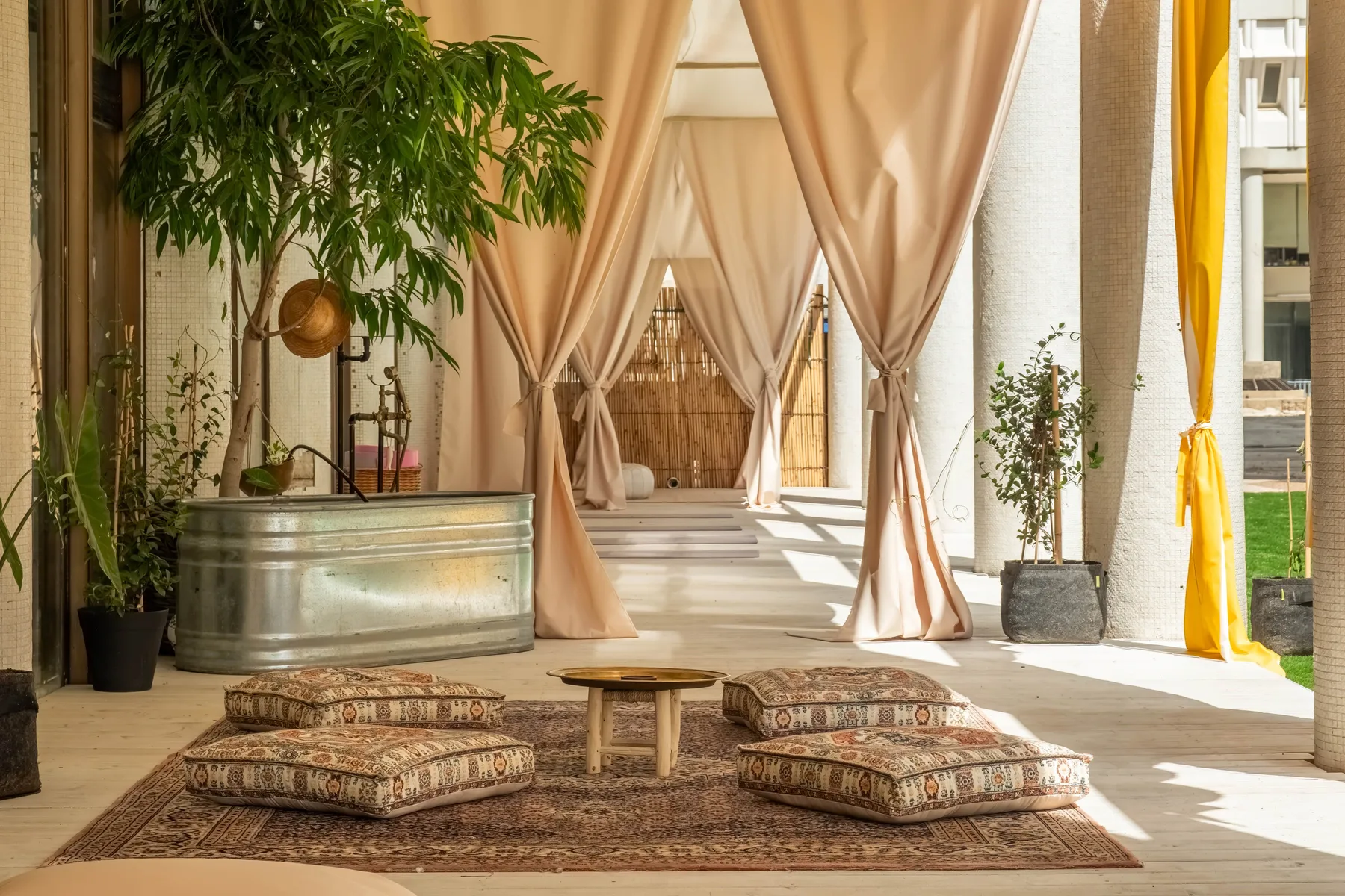 Representative hotel space: A sunlit lounge with floor cushions and curtains opening onto a bright courtyard.