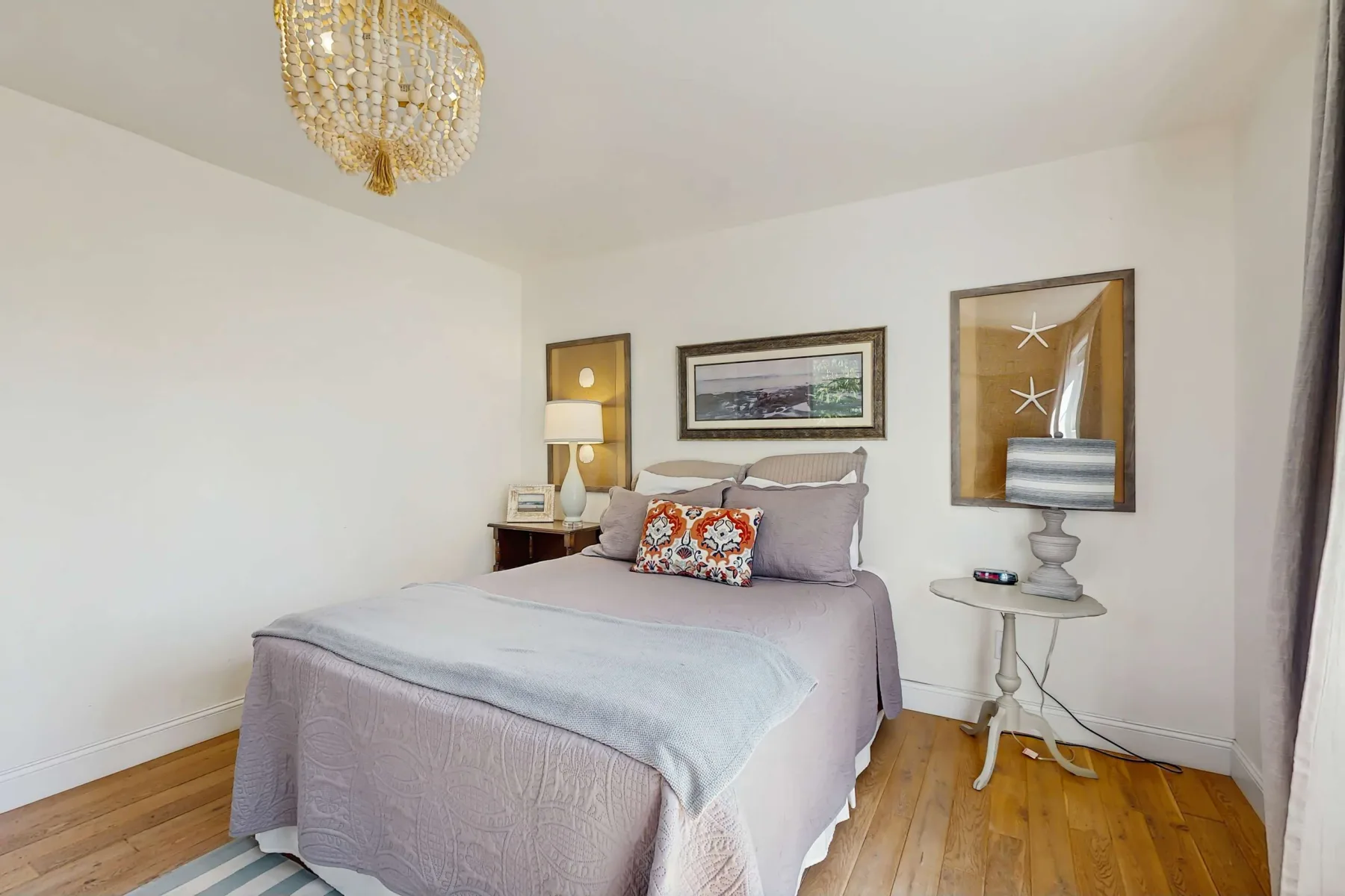 Un dormitorio con una cama bien tendida y cuadros en la pared.