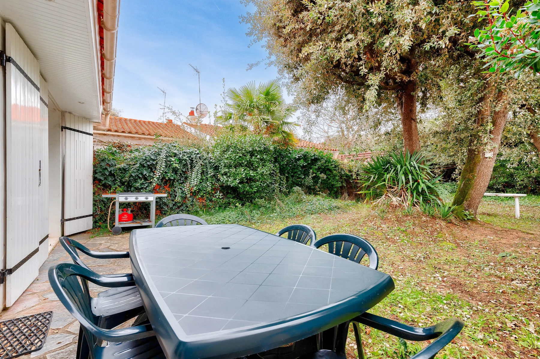 An outdoor patio with a dining table and surrounding greenery.