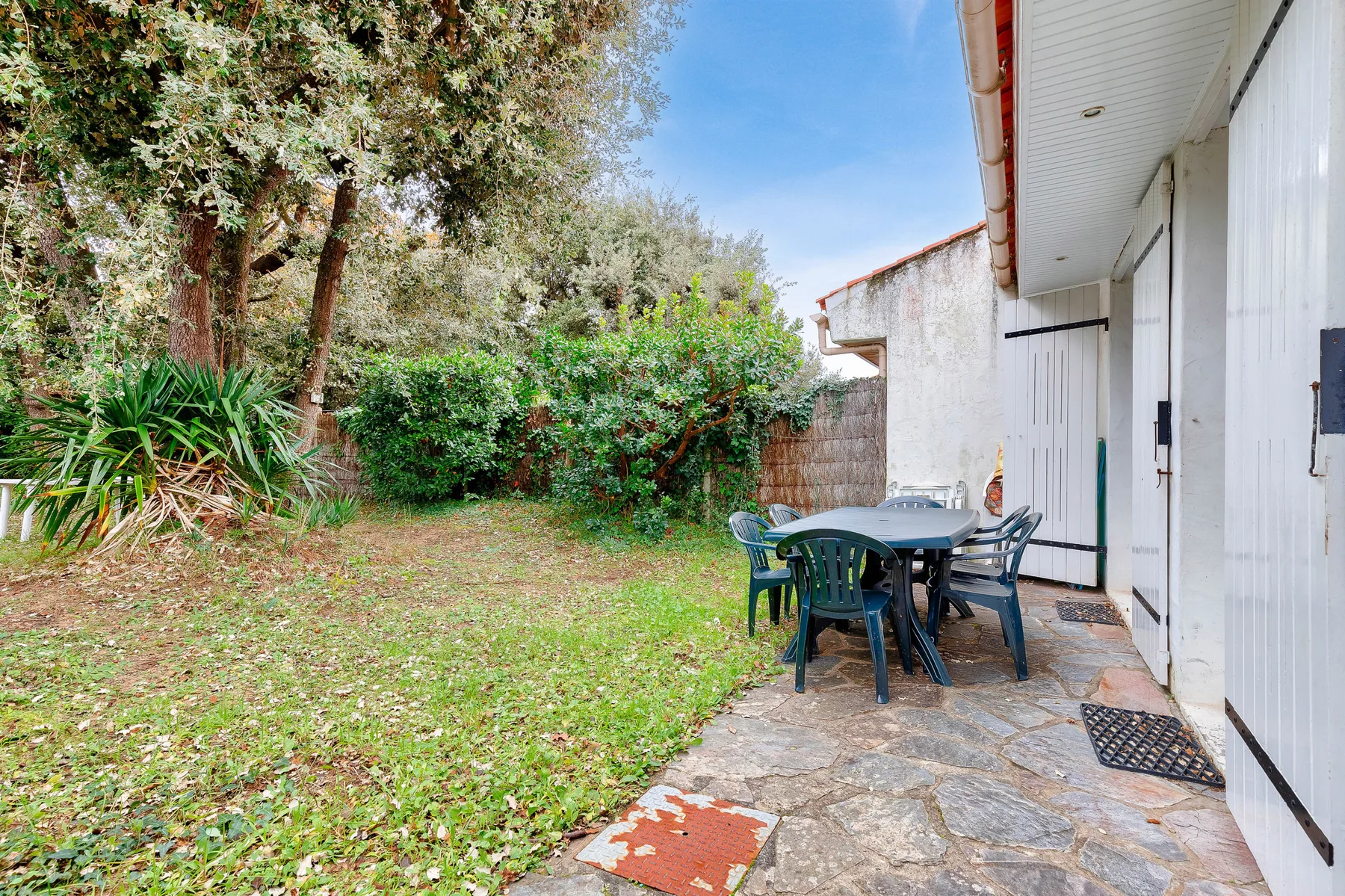 A garden patio with outdoor seating beside a leafy lawn.