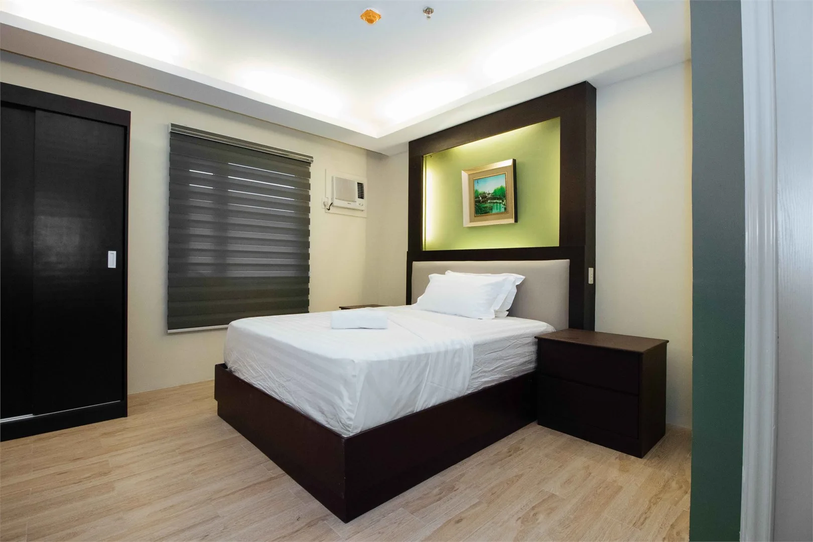 Espacio representativo del hotel: Un dormitorio con una cama bien tendida bajo un cuadro enmarcado.