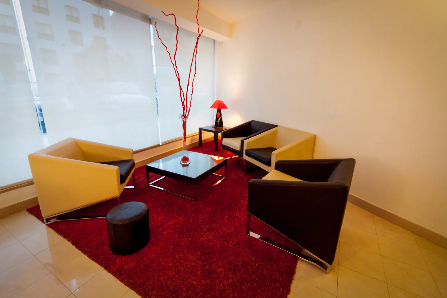 Espacio representativo del hotel: Un salón de hotel tiene varios asientos alrededor de una mesa baja sobre una alfombra roja.