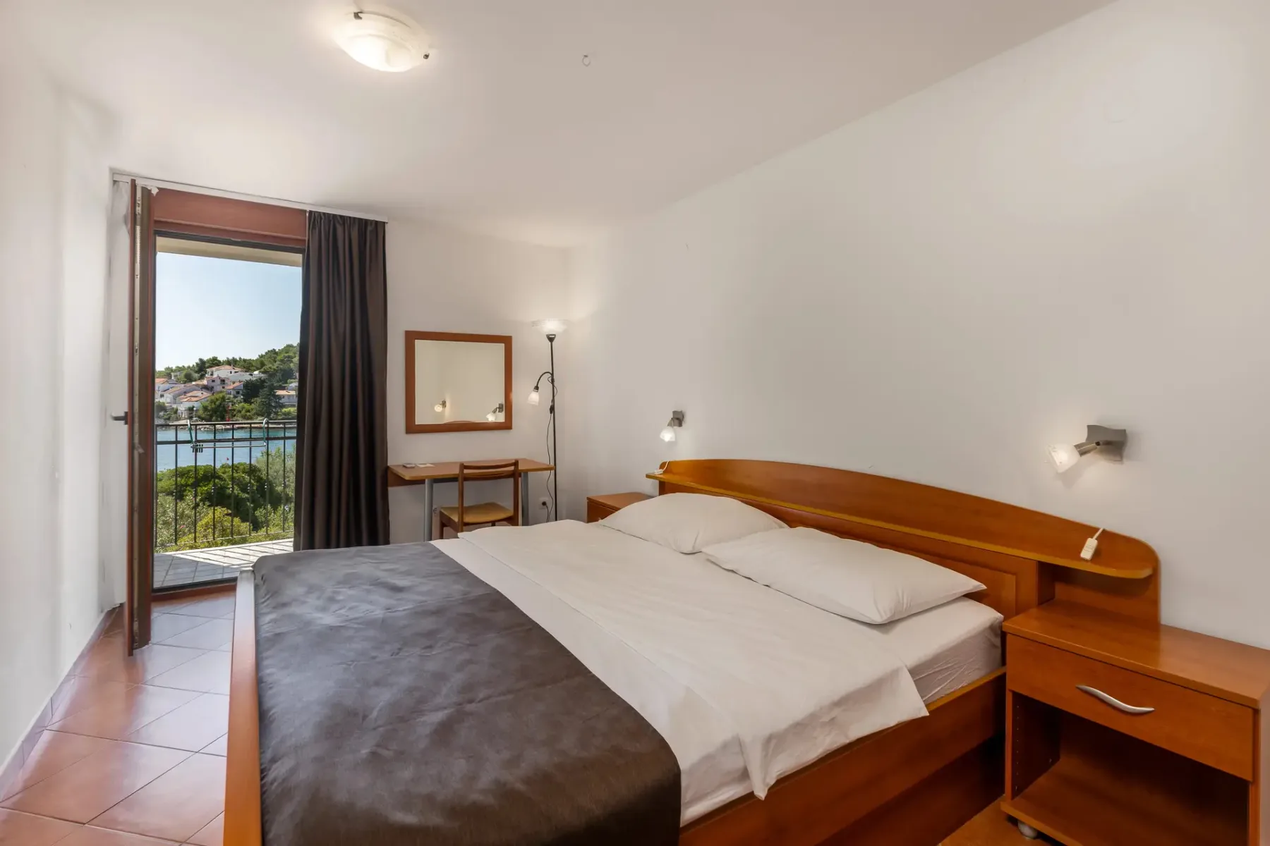 Espacio representativo del hotel: Un dormitorio de hotel con una cama y la puerta del balcón abierta.