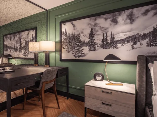 Representative hotel space: A bedroom corner with a desk, bedside table, and snowy mountain artwork.