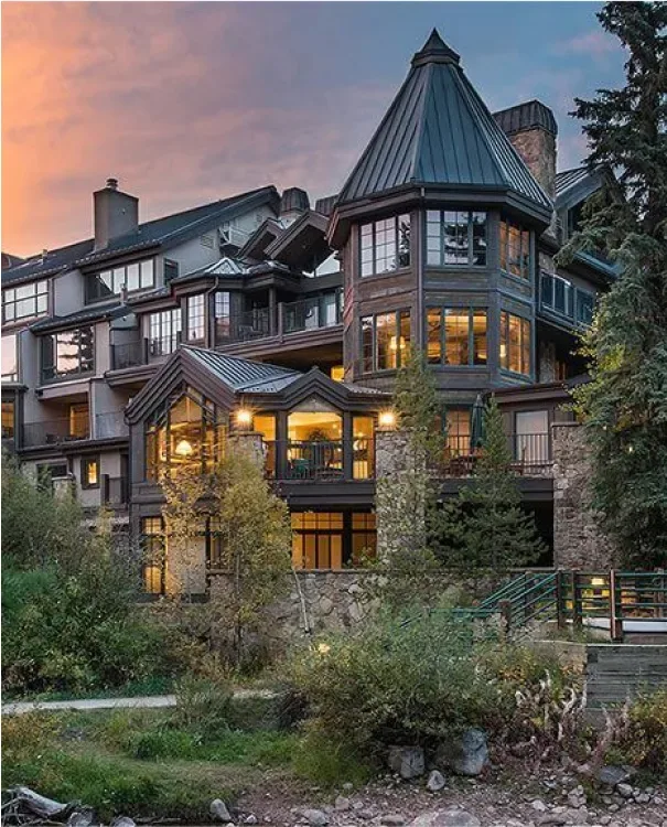 Representative hotel space: A multi-level building with timber-framed windows stands among trees at sunset.