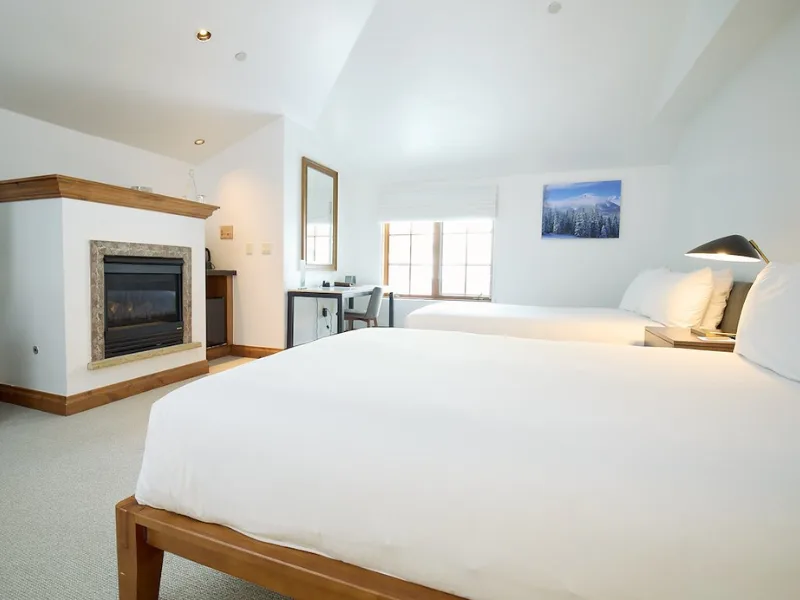 Representative hotel space: A bright bedroom with white bedding, a fireplace, and a desk by the window.