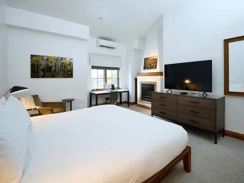 Representative hotel space: A bright bedroom with a large bed, television, and fireplace.
