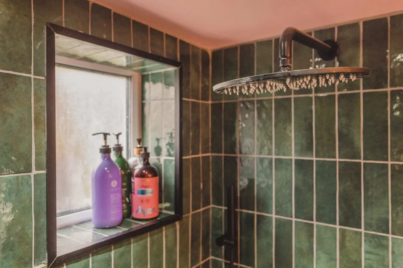 A tiled shower area with a large overhead showerhead and a window.