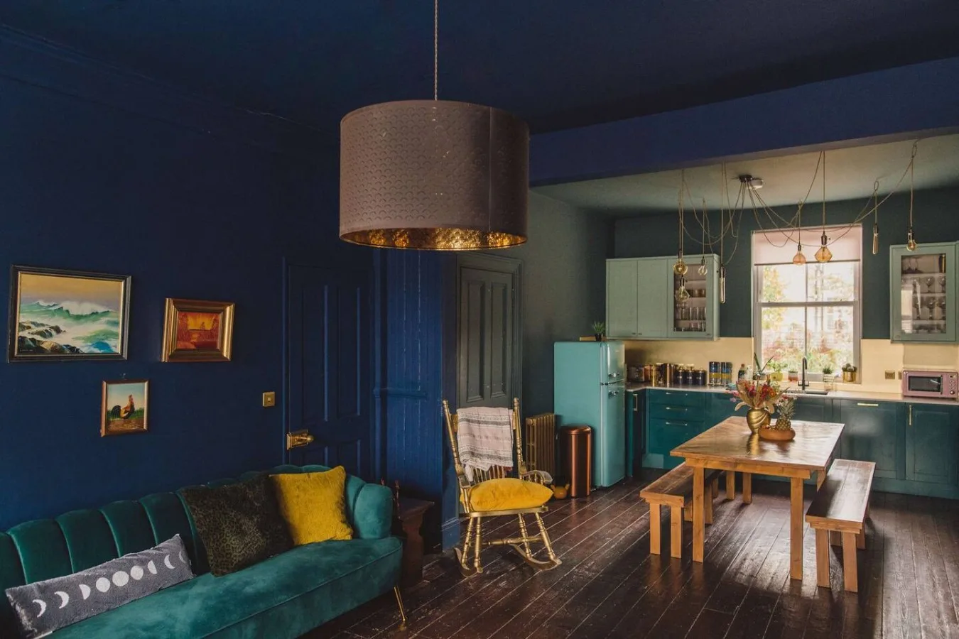 A colorful living and dining area with teal seating and a wooden table.