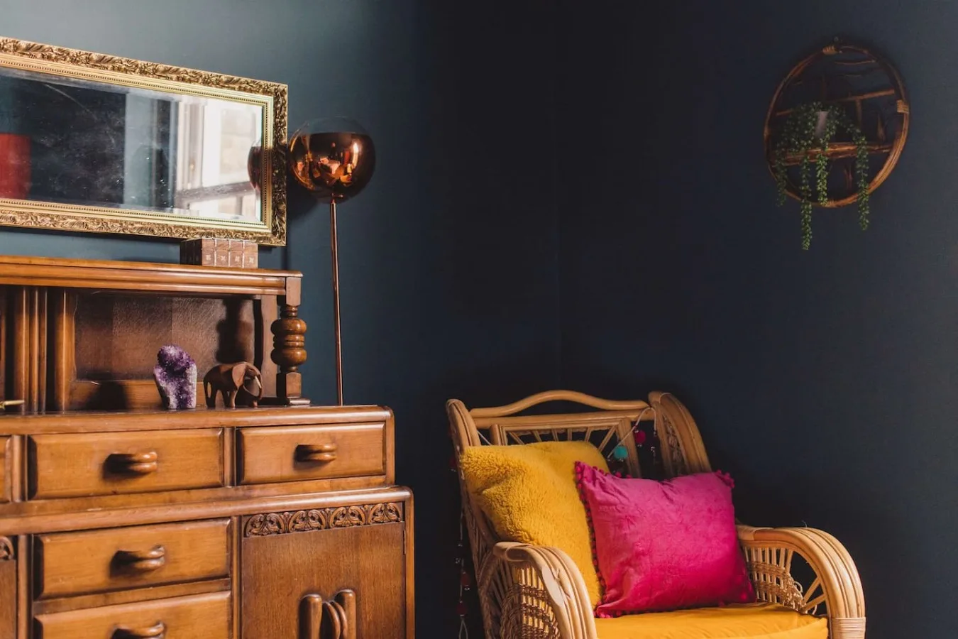 A sitting area with a wooden cabinet and a wicker chair with colorful cushions.