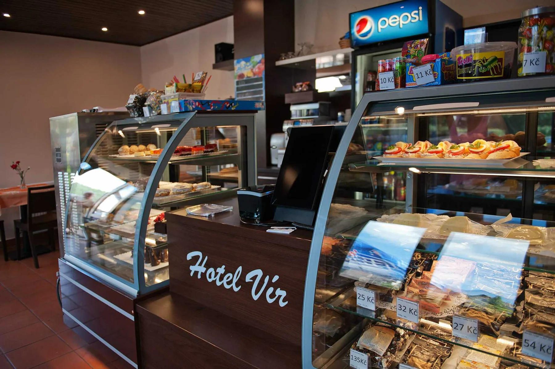 Espacio representativo del hotel: Un mostrador de cafetería de hotel exhibe pasteles y aperitivos en vitrinas.