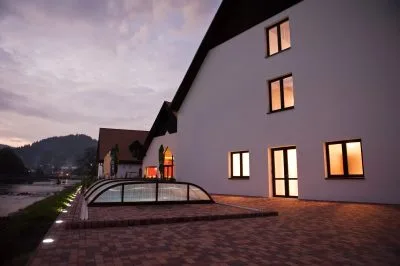 Espacio representativo del hotel: Un edificio moderno con ventanas iluminadas junto a una terraza pavimentada al anochecer.