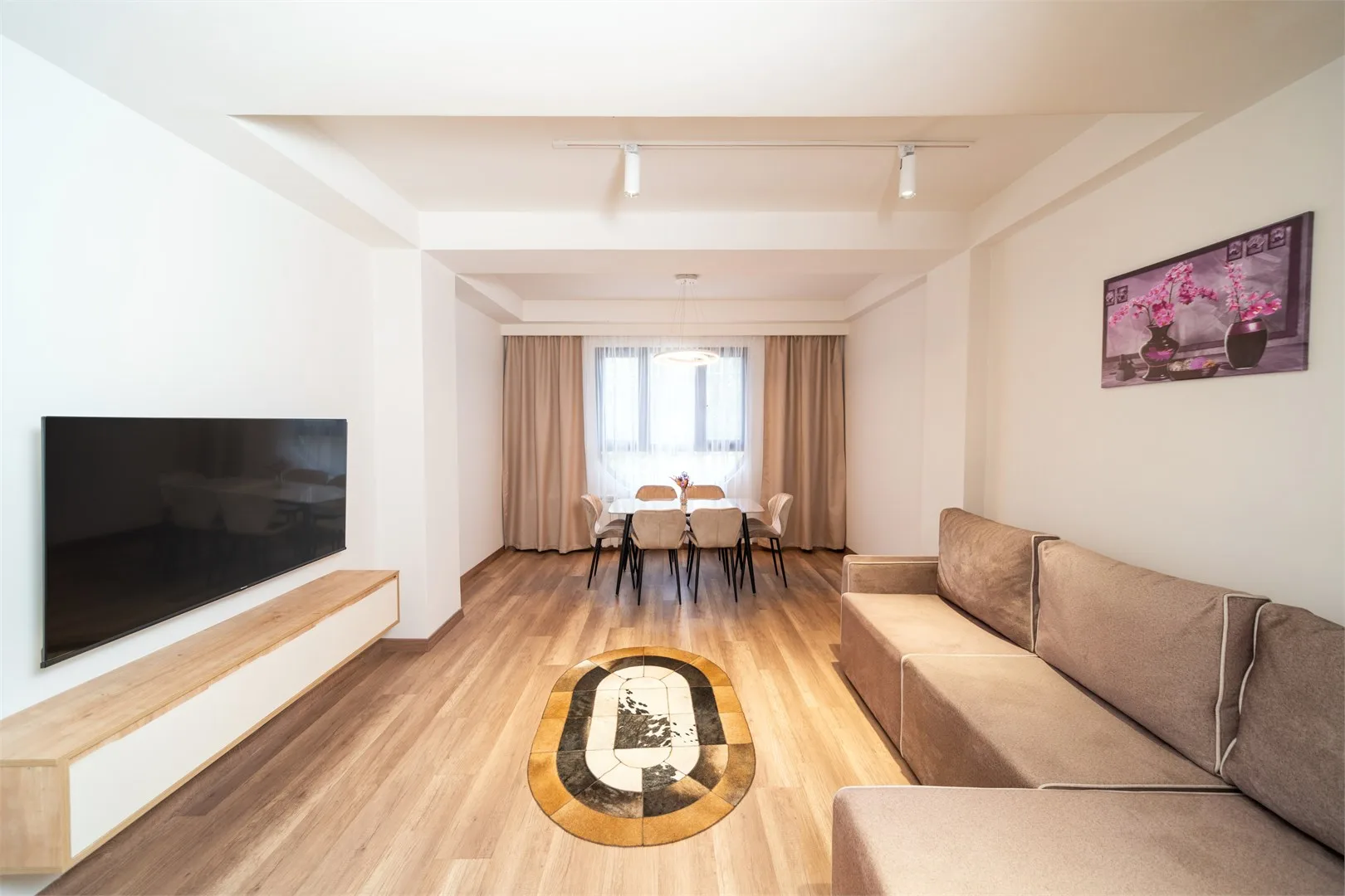 Representative hotel space: Living room with a television, seating, and a dining area by the window.
