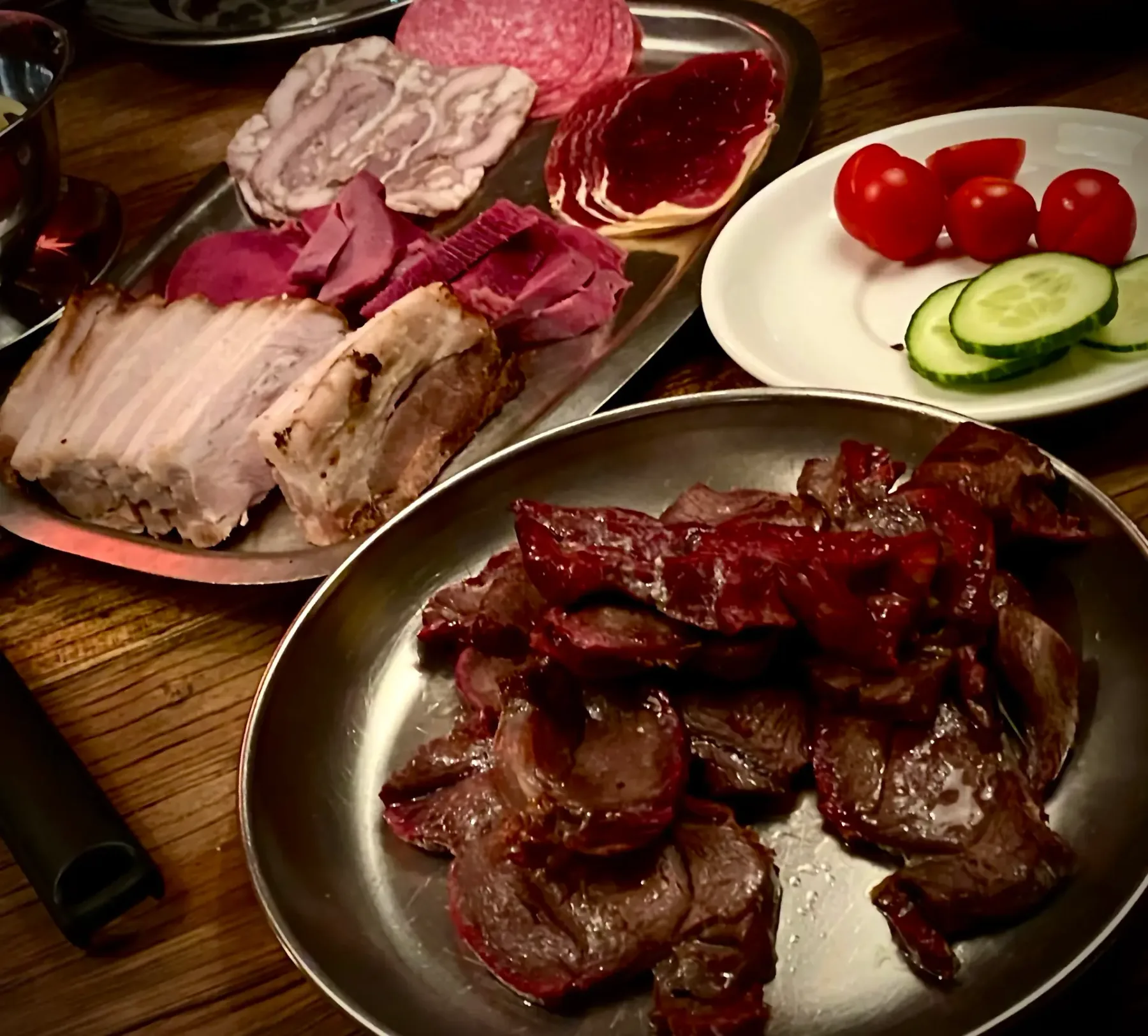 Espacio representativo del hotel: Platos de carnes en lonchas y verduras están dispuestos sobre una mesa de madera.