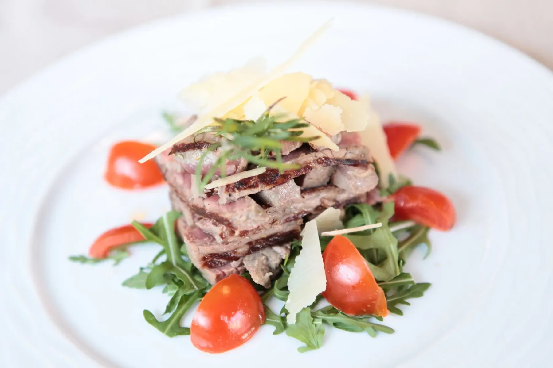 Espacio representativo del hotel: Un plato de carne se sirve con hojas verdes, tomates y queso en láminas.