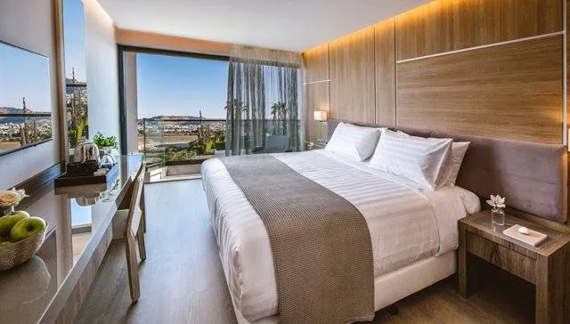 Espacio representativo del hotel: Dormitorio de hotel con una cama grande junto a ventanales.