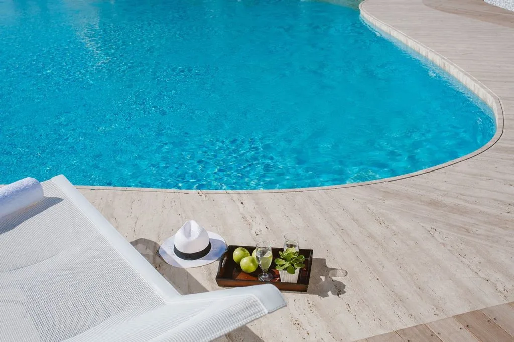 Espacio representativo del hotel: Una piscina curva junto a una terraza clara y asientos para descansar.
