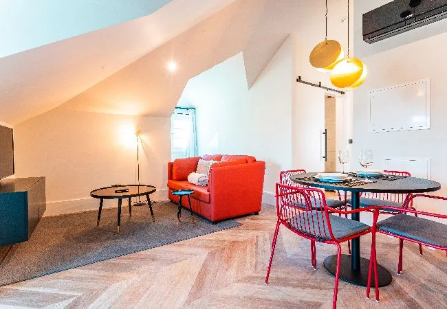 A bright open-plan living and dining area with red seating and a round table.