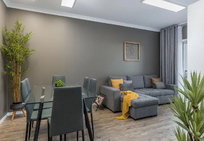 A living room with a gray sectional sofa and a glass dining table.