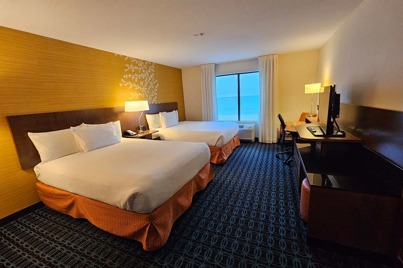 Espacio representativo del hotel: Un dormitorio de hotel con camas, un escritorio y una ventana con vista al agua.