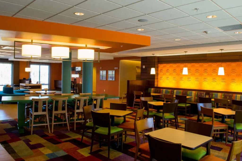 Espacio representativo del hotel: Comedor de hotel con mesas, sillas e iluminación cálida de tono naranja.