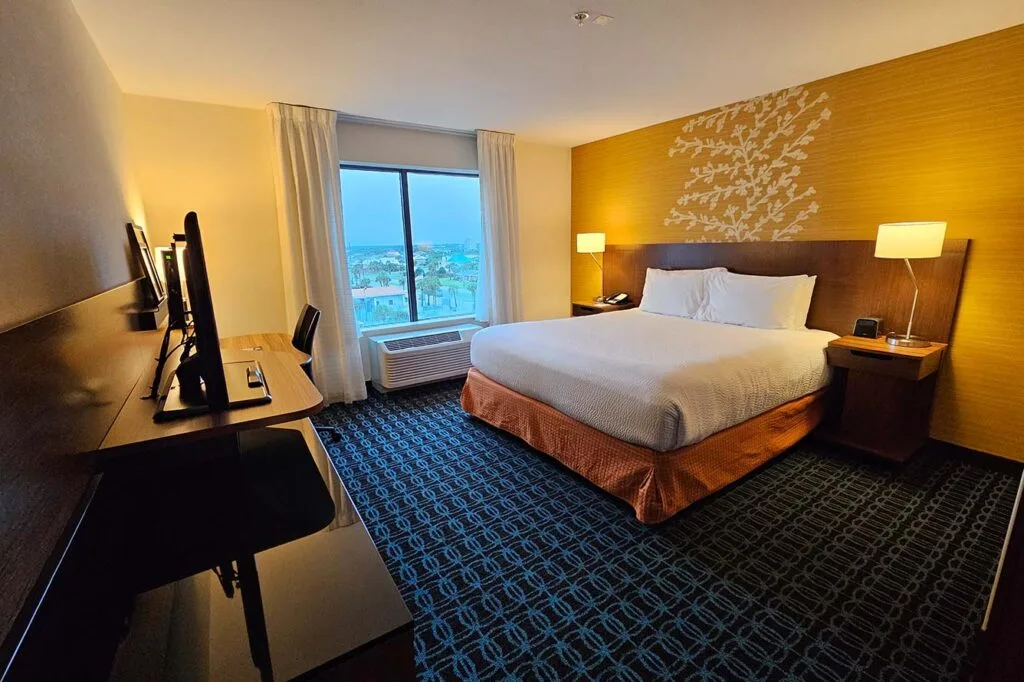 Espacio representativo del hotel: Un dormitorio de hotel con una cama grande, lámparas de noche y una ventana.