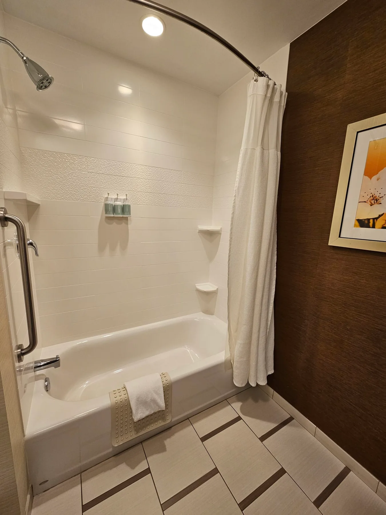 Espacio representativo del hotel: Un baño con bañera, cortina de ducha y suelo de baldosas.