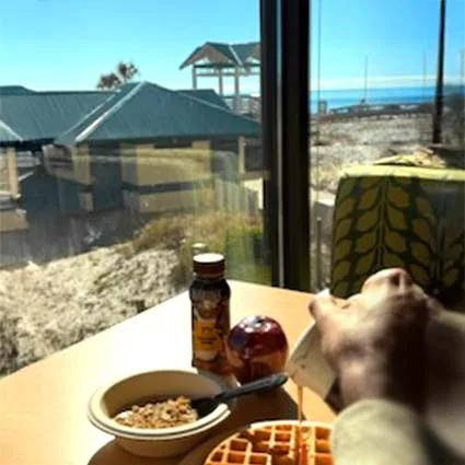 Espacio representativo del hotel: El desayuno está sobre una mesa junto a una ventana con vista a la playa.