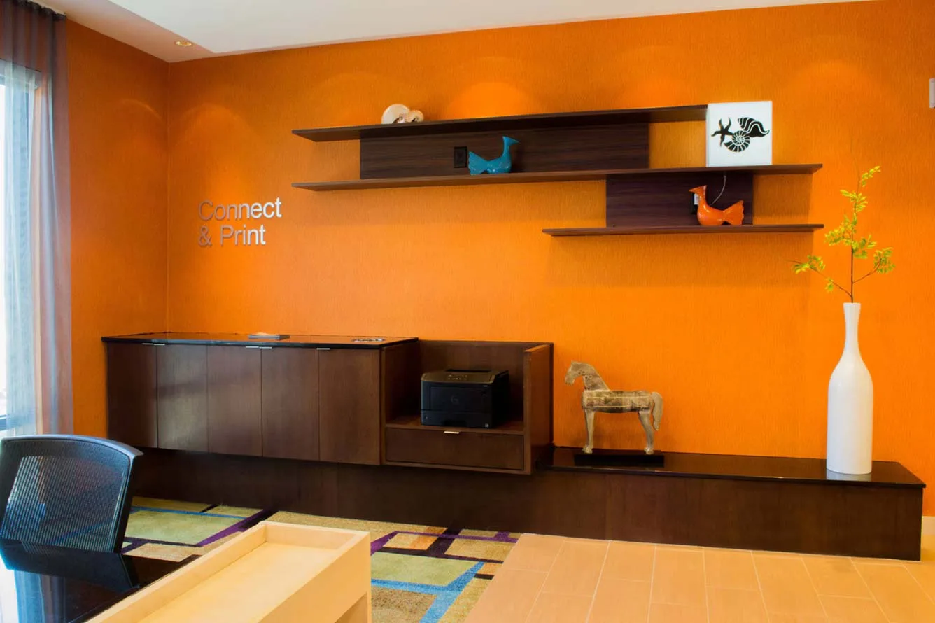 Espacio representativo del hotel: Una habitación de paredes naranjas con gabinetes oscuros y estantes flotantes.
