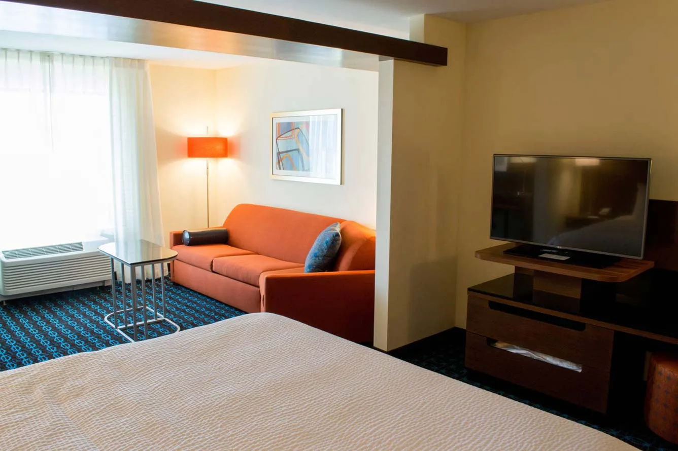 Espacio representativo del hotel: Una habitación de hotel tiene una cama, asientos naranjas y un televisor.