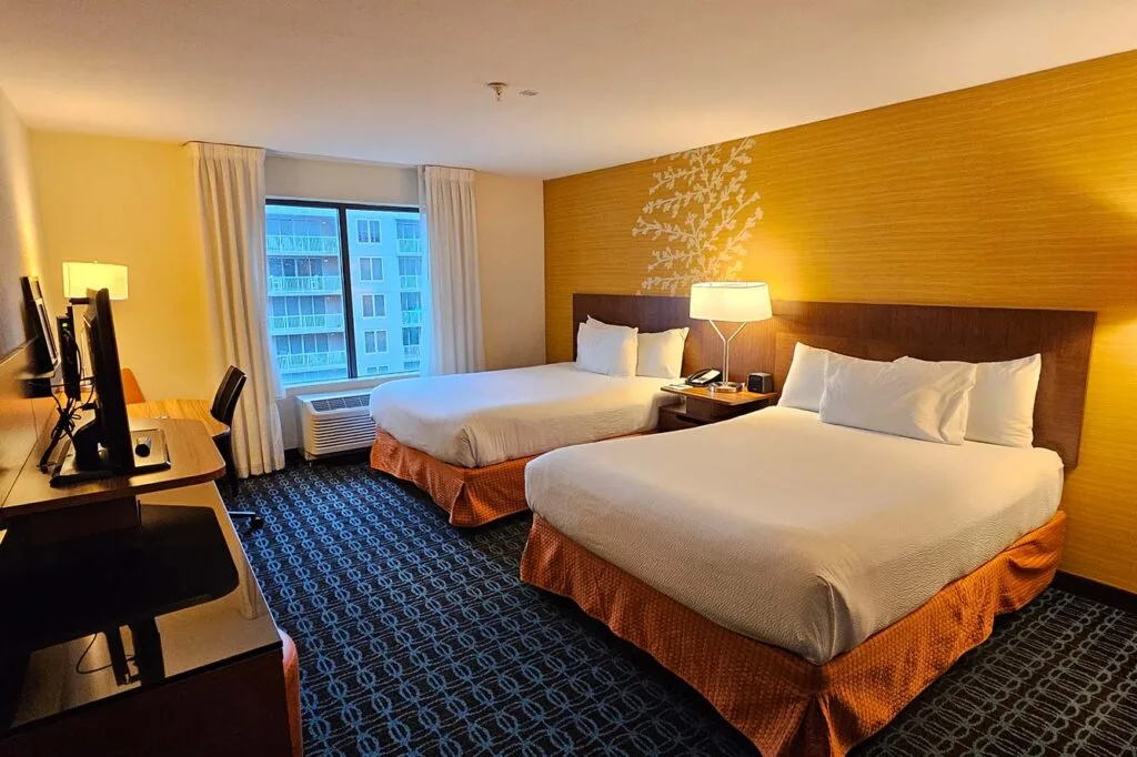 Espacio representativo del hotel: Un dormitorio de hotel con dos camas y un escritorio junto a la ventana.