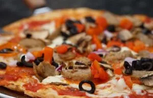 Espacio representativo del hotel: Primer plano de una pizza con aceitunas, champiñones y pimientos.