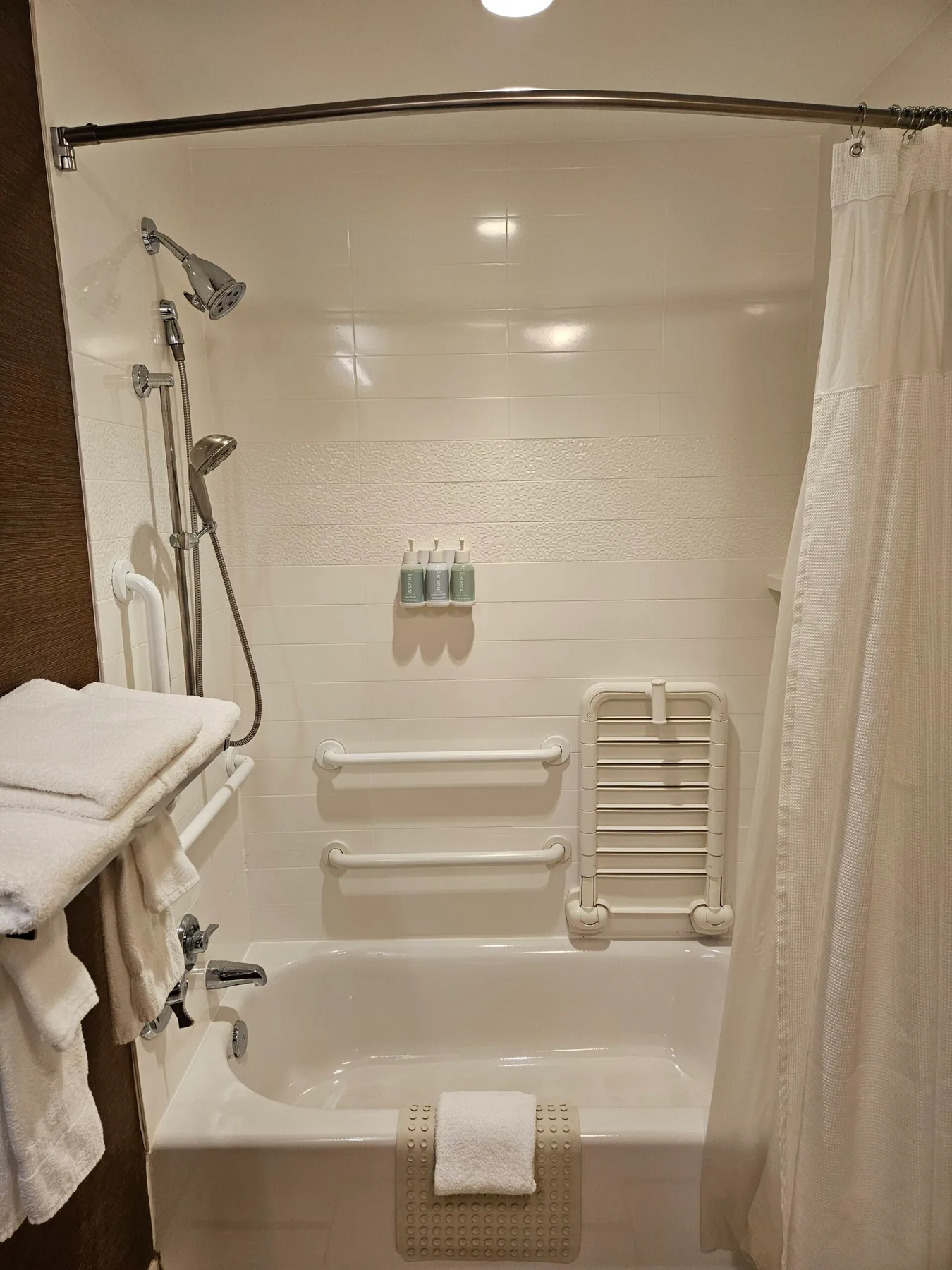 Espacio representativo del hotel: Un baño con bañera, ducha y barras de apoyo.