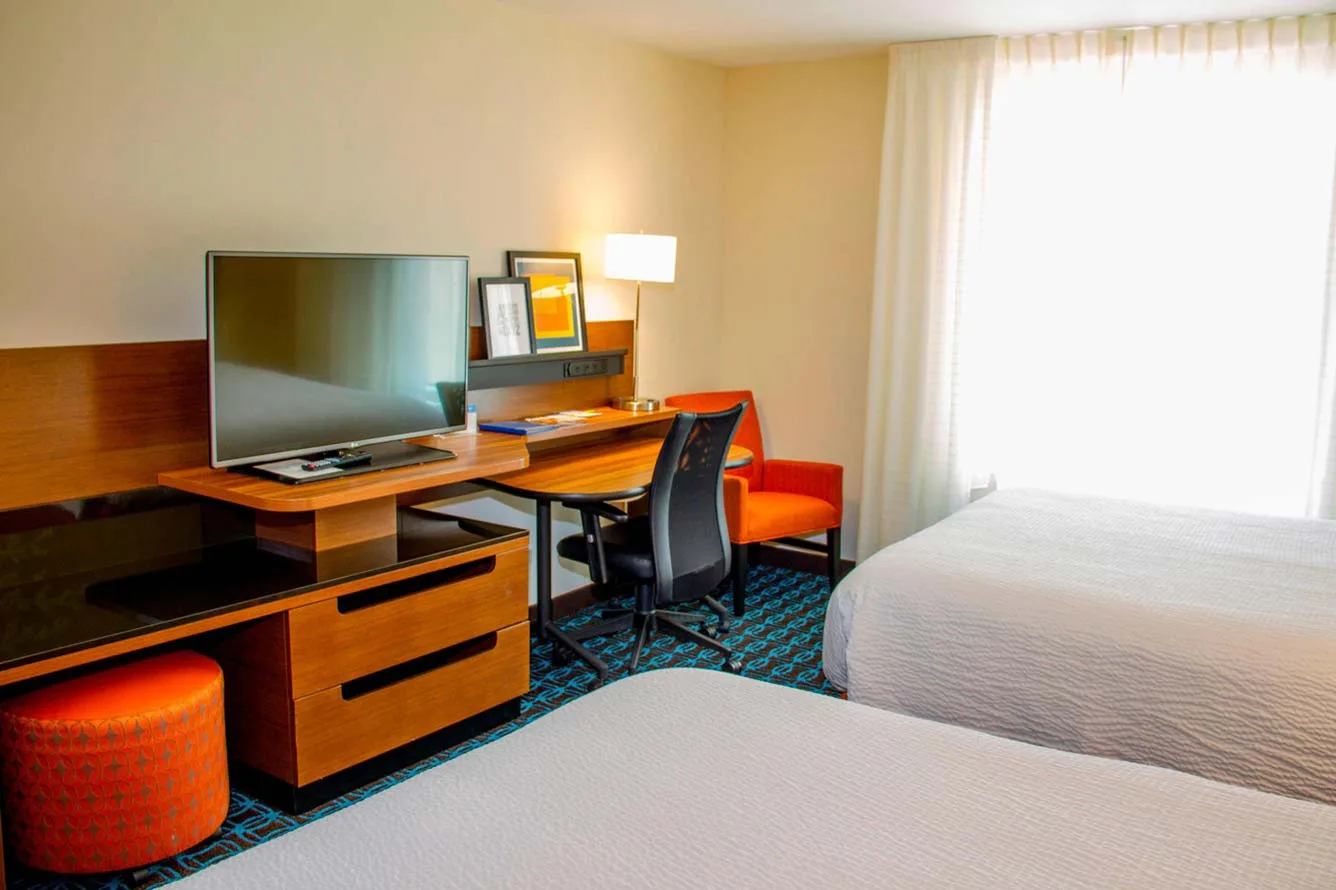 Espacio representativo del hotel: Dormitorio de hotel con dos camas, un escritorio y un televisor.