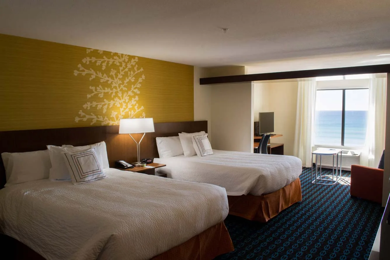 Espacio representativo del hotel: Dormitorio de hotel con dos camas y una ventana amplia con vista al agua.