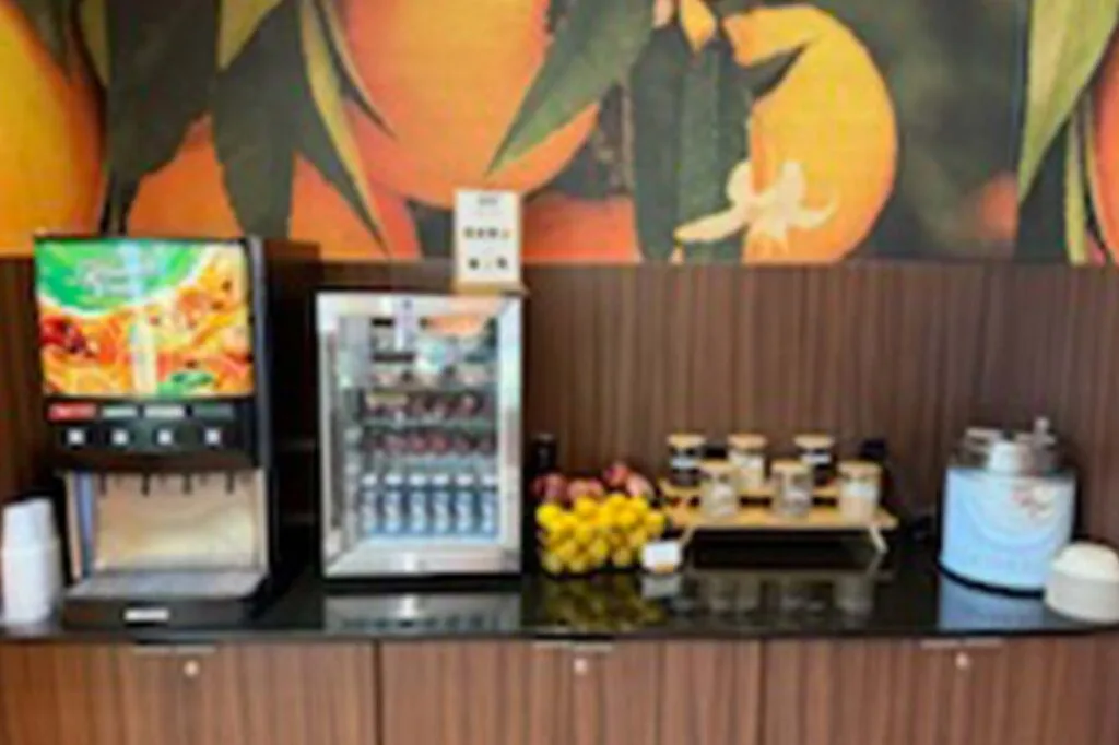Espacio representativo del hotel: Una estación de autoservicio de bebidas y aperitivos con un dispensador y suministros sobre la encimera.