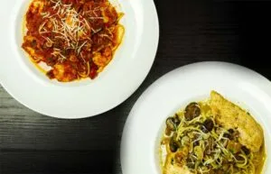 Espacio representativo del hotel: Se muestran dos platos de pasta sobre una mesa oscura.