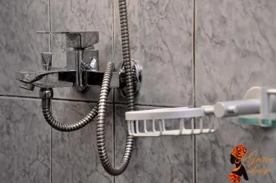 Espacio representativo del hotel: Zona de ducha con azulejos, una ducha de mano y accesorios en la pared.