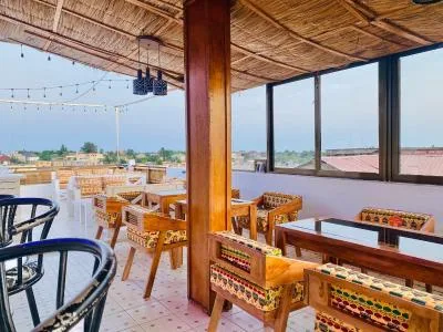 Espacio representativo del hotel: Un comedor cubierto con mesas y asientos de madera junto a grandes ventanas.