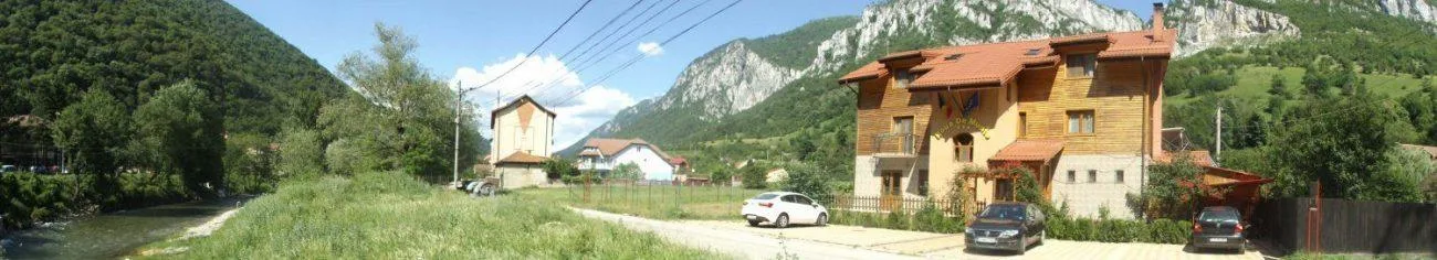 Espacio representativo del hotel: Escena junto a la carretera en la montaña, con un edificio de madera y autos estacionados.