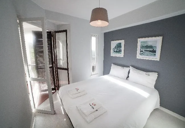 Un dormitorio con una cama bien tendida y cuadros enmarcados en la pared.