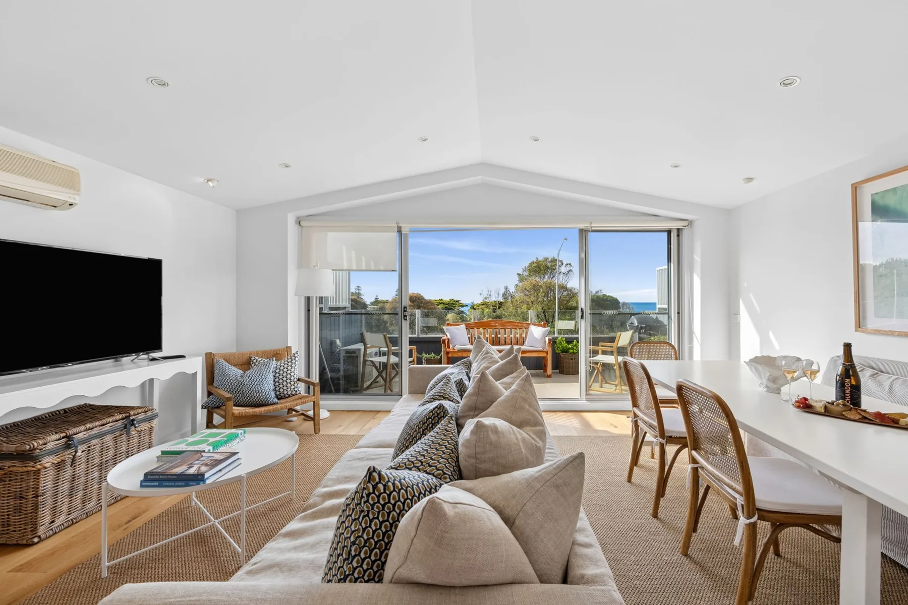 A bright living room with seating and wide glass doors opening onto a balcony.
